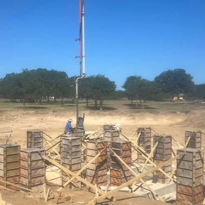 A man is standing next to a crane on a construction site.