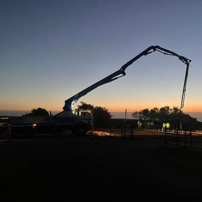 A truck with a crane attached to it is driving down a road at night.