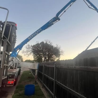 A concrete pump is being used to pour concrete into a fence.