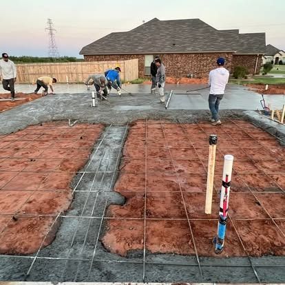 A group of people are working on a concrete floor in front of a house.