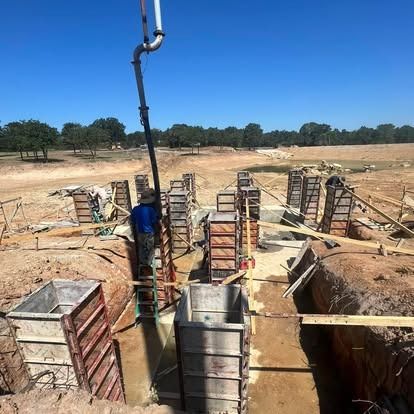 A man is pouring concrete into a hole in a construction site.