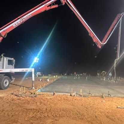 A concrete pump is being used to pour concrete on a construction site at night