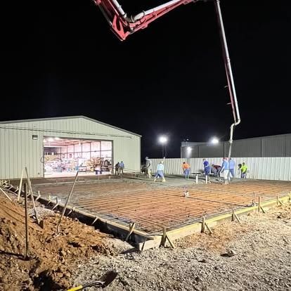 A concrete pump is being used to pour concrete on a construction site at night.
