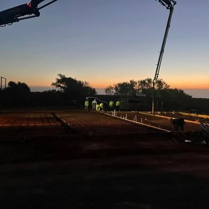 A group of people are working on a construction site at night.
