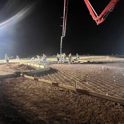 A group of people are working on a construction site at night.