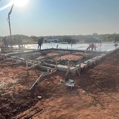 A group of construction workers are working on a concrete floor.