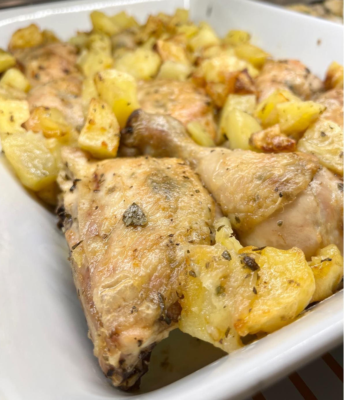 Pollo arrosto e patate in una teglia bianca: cibo dorato e appetitoso.