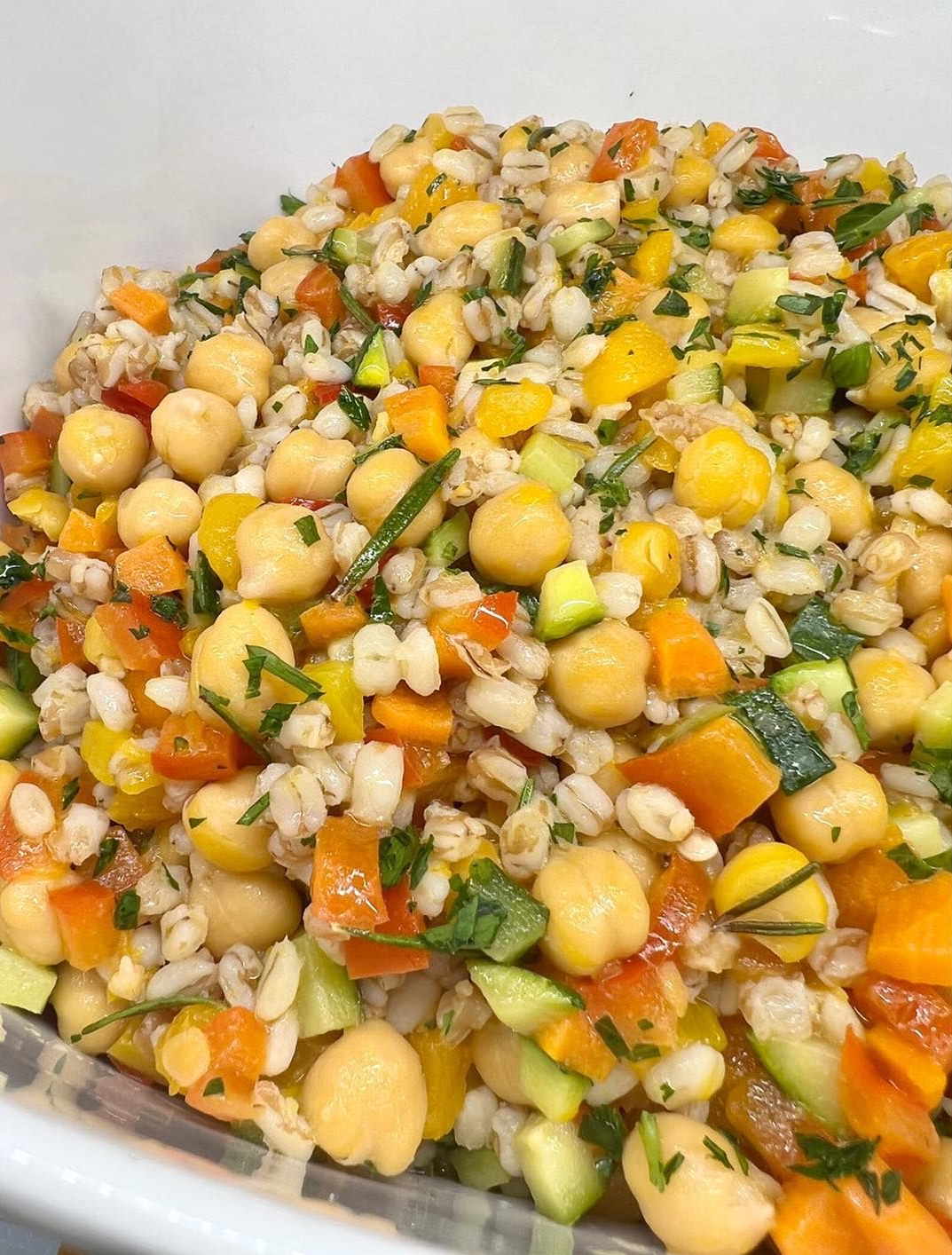 Insalata di ceci, orzo e verdure: ceci, verdure tritate in una ciotola bianca.