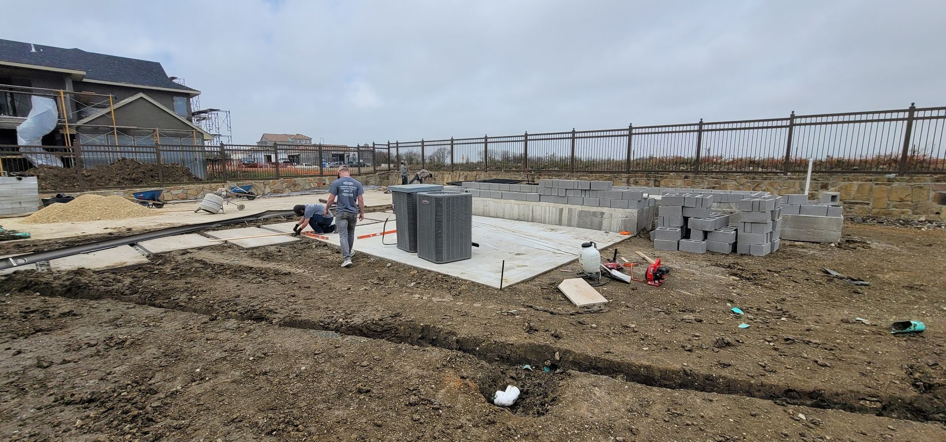 A man is standing in a dirt field in front of a house under construction.