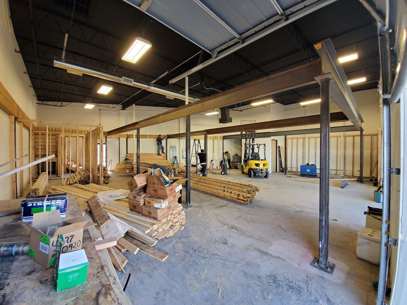 A large building under construction with a forklift in the middle of the room.