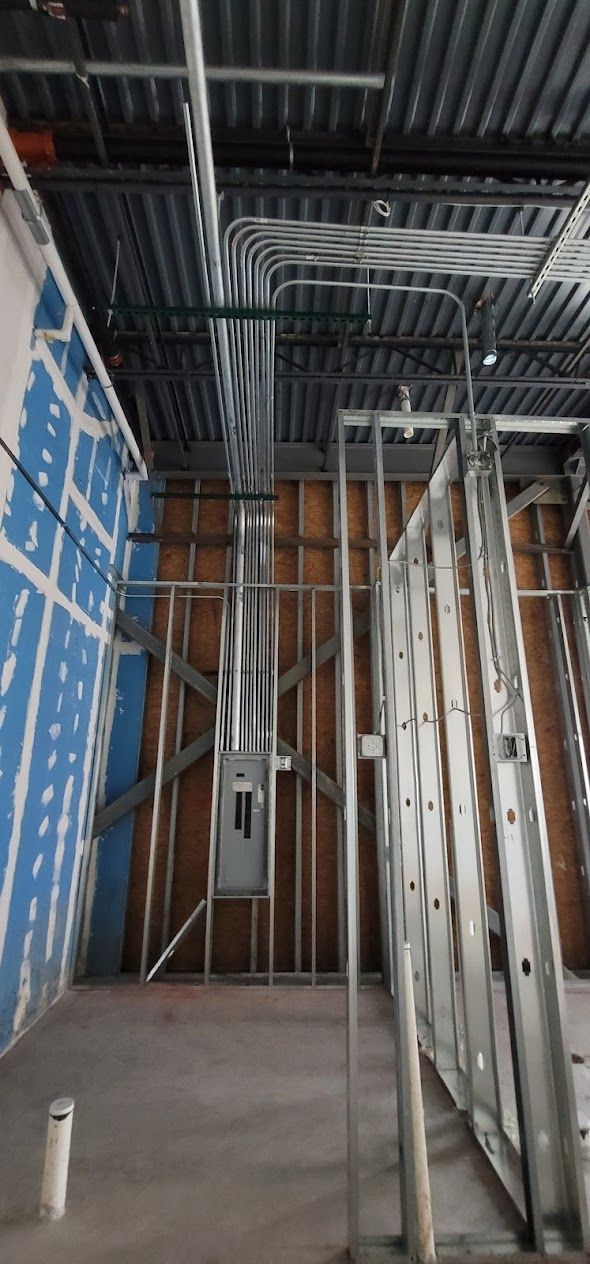 A building under construction with a lot of pipes hanging from the ceiling.