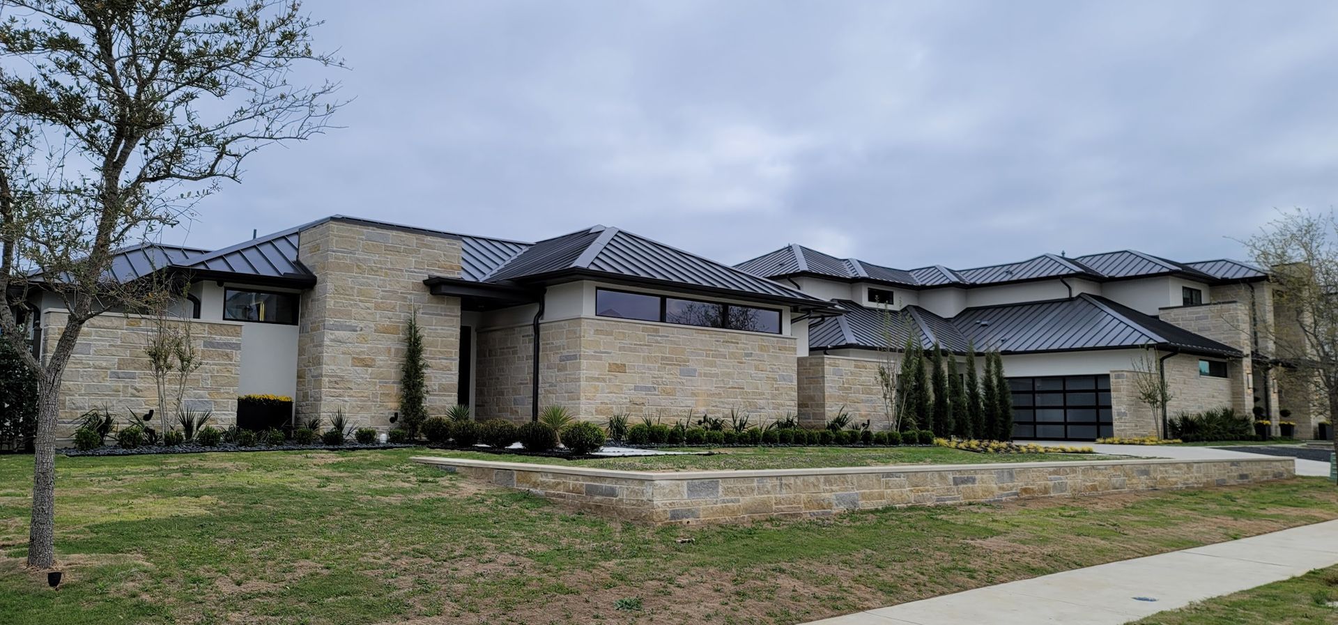 A large house with a metal roof is sitting on top of a lush green lawn.