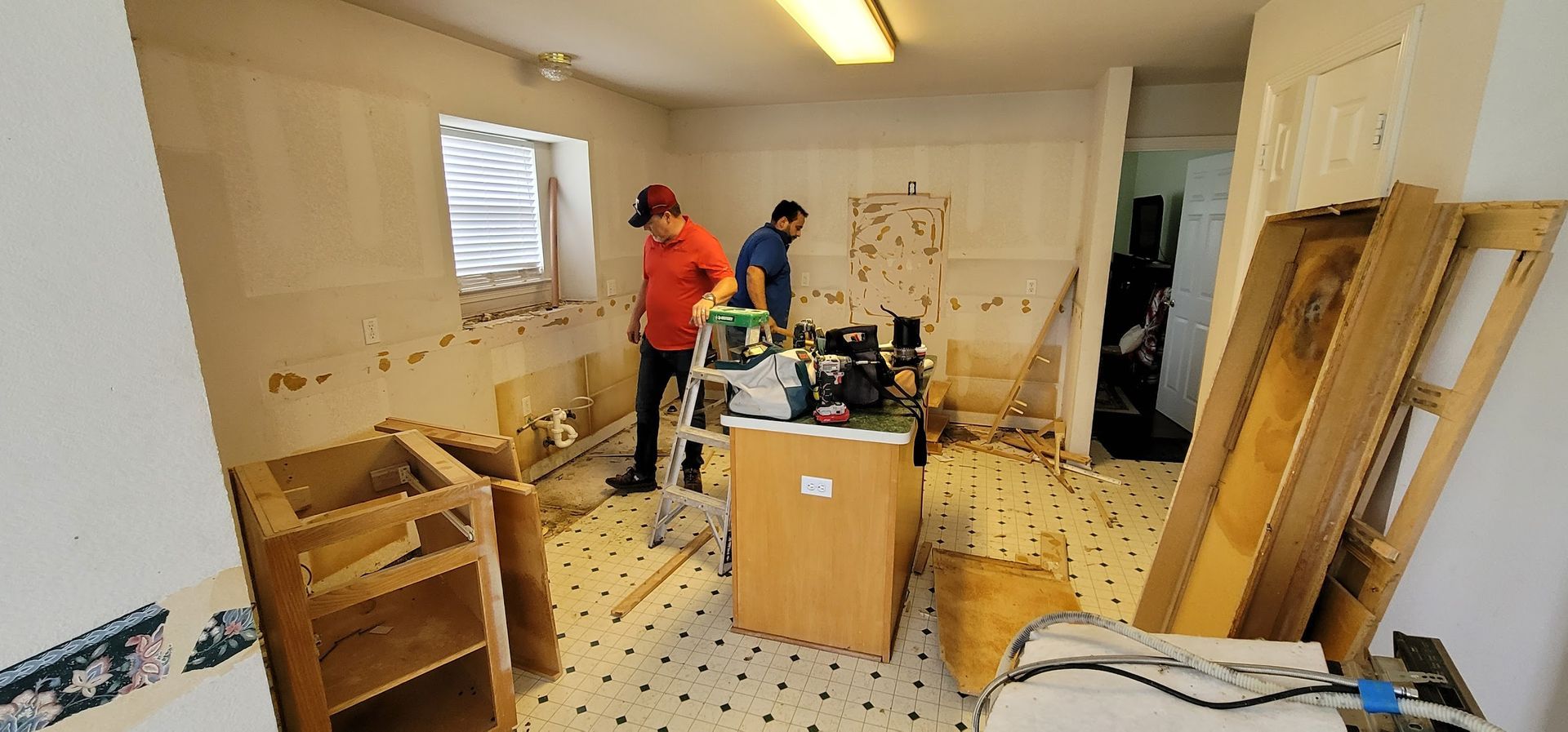 Two men are working in a messy kitchen.