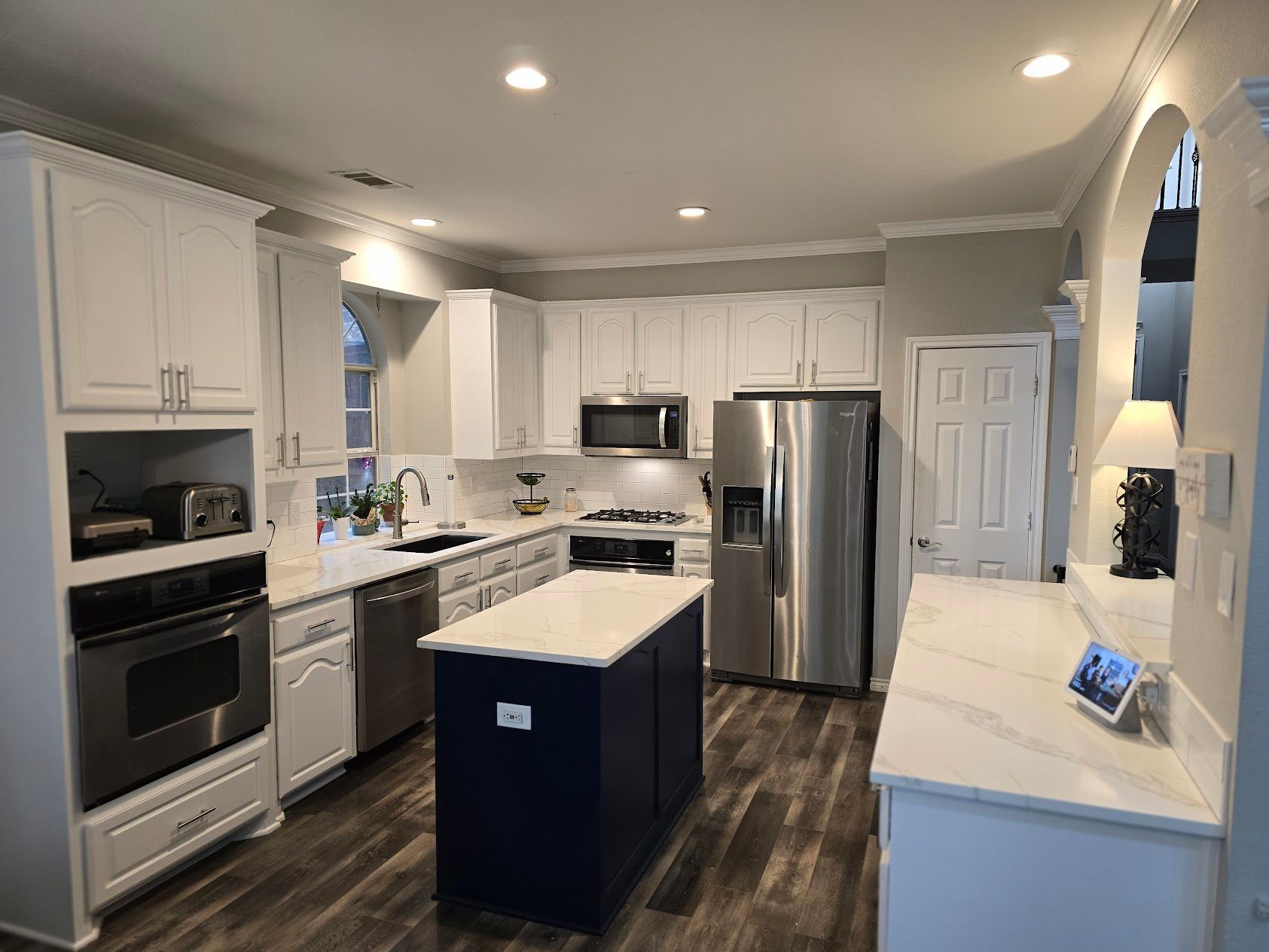 A kitchen with white cabinets , stainless steel appliances , and a large island.