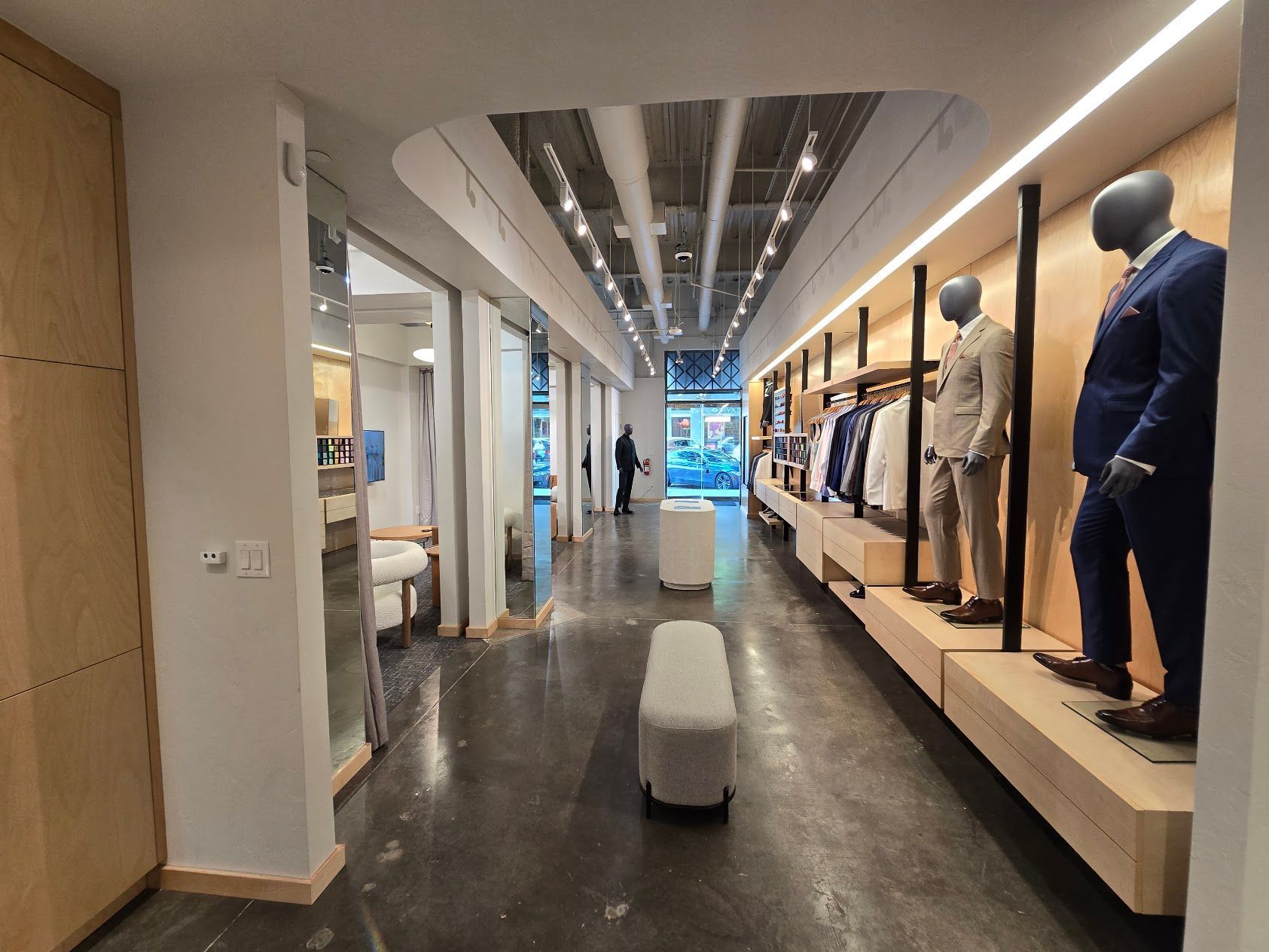 A long hallway with mannequins displaying suits in a clothing store.