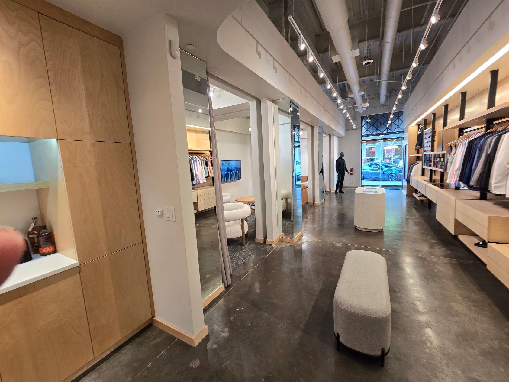 A person is standing in a long hallway in a clothing store.