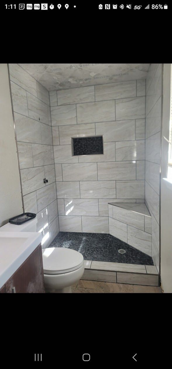 A bathroom with a toilet , shower , and sink.