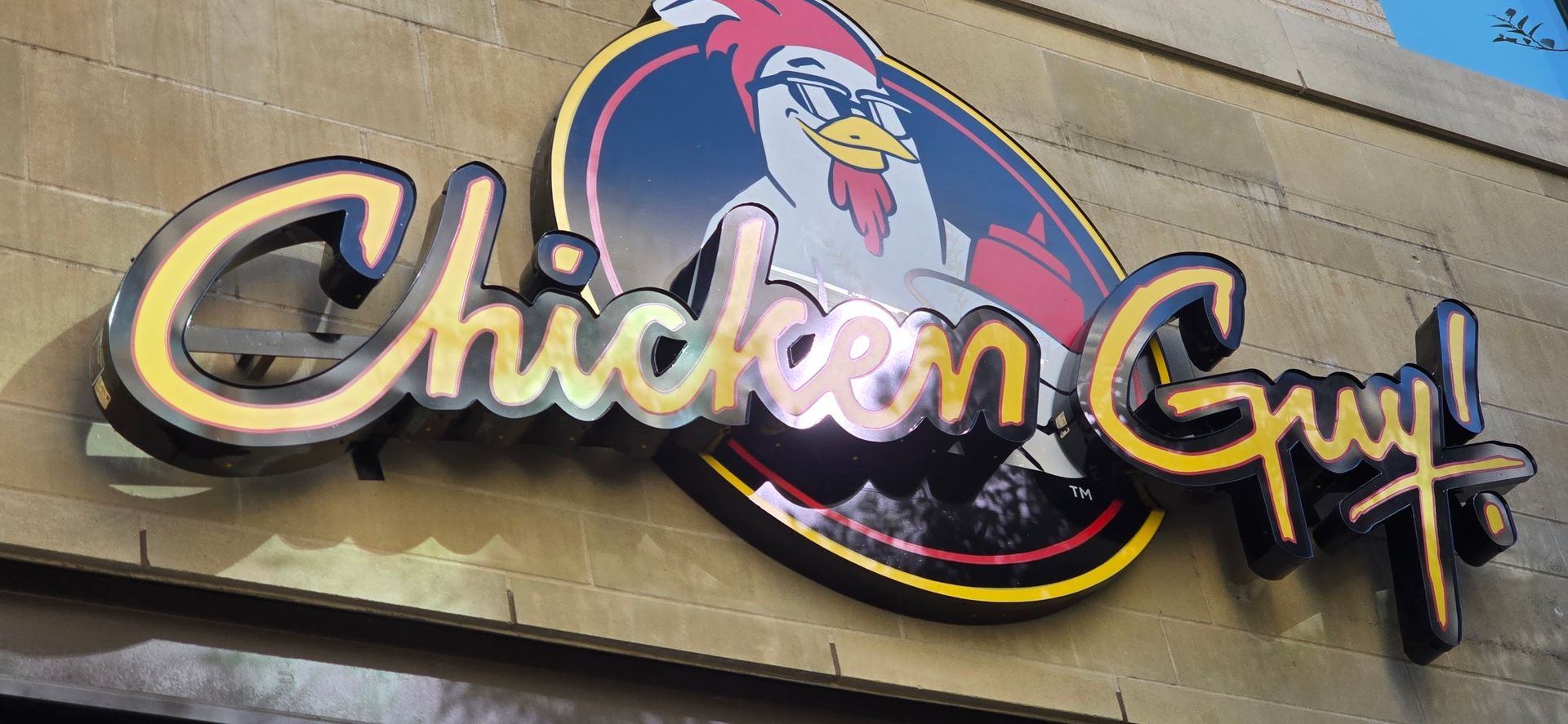 A close up of a chicken guy sign on a building
