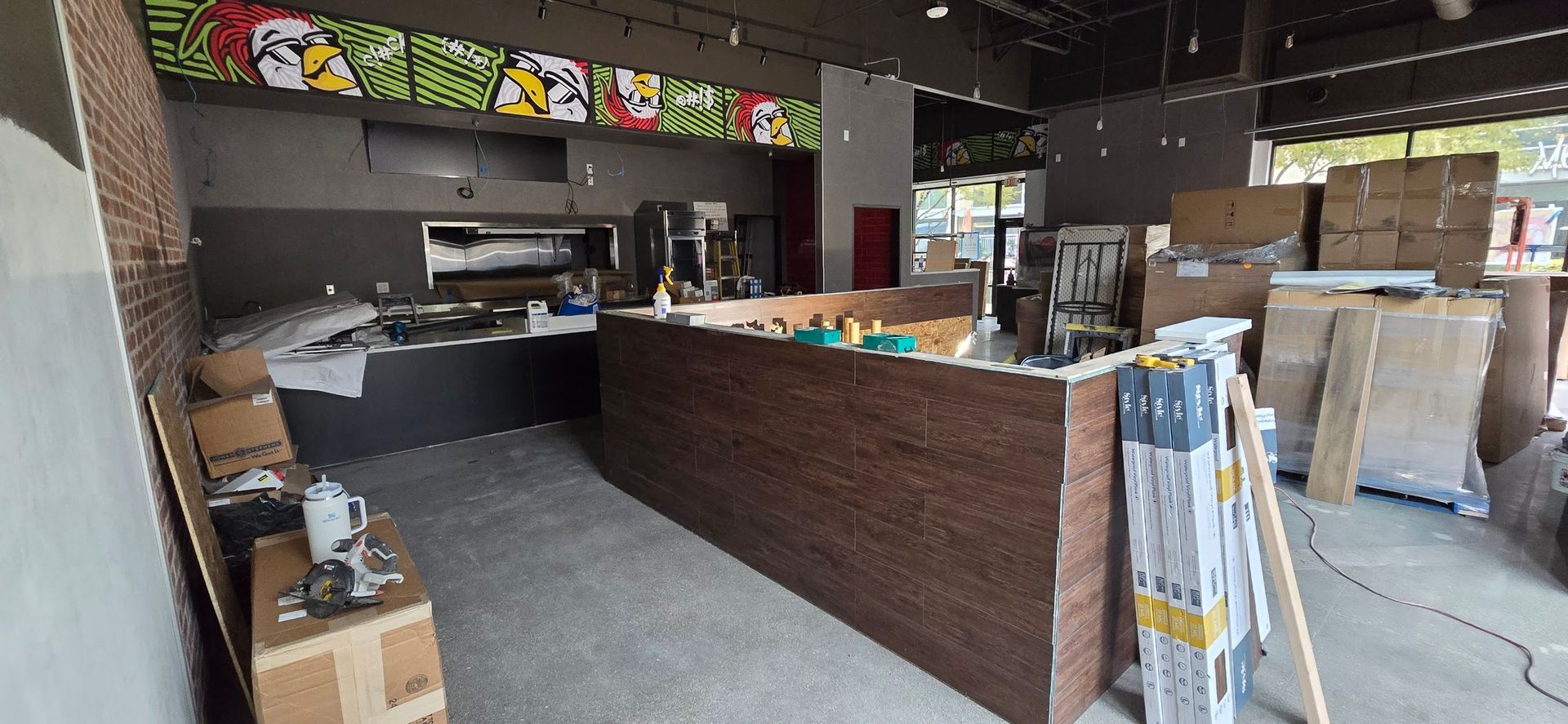 A kitchen in a building under construction with boxes on the floor.