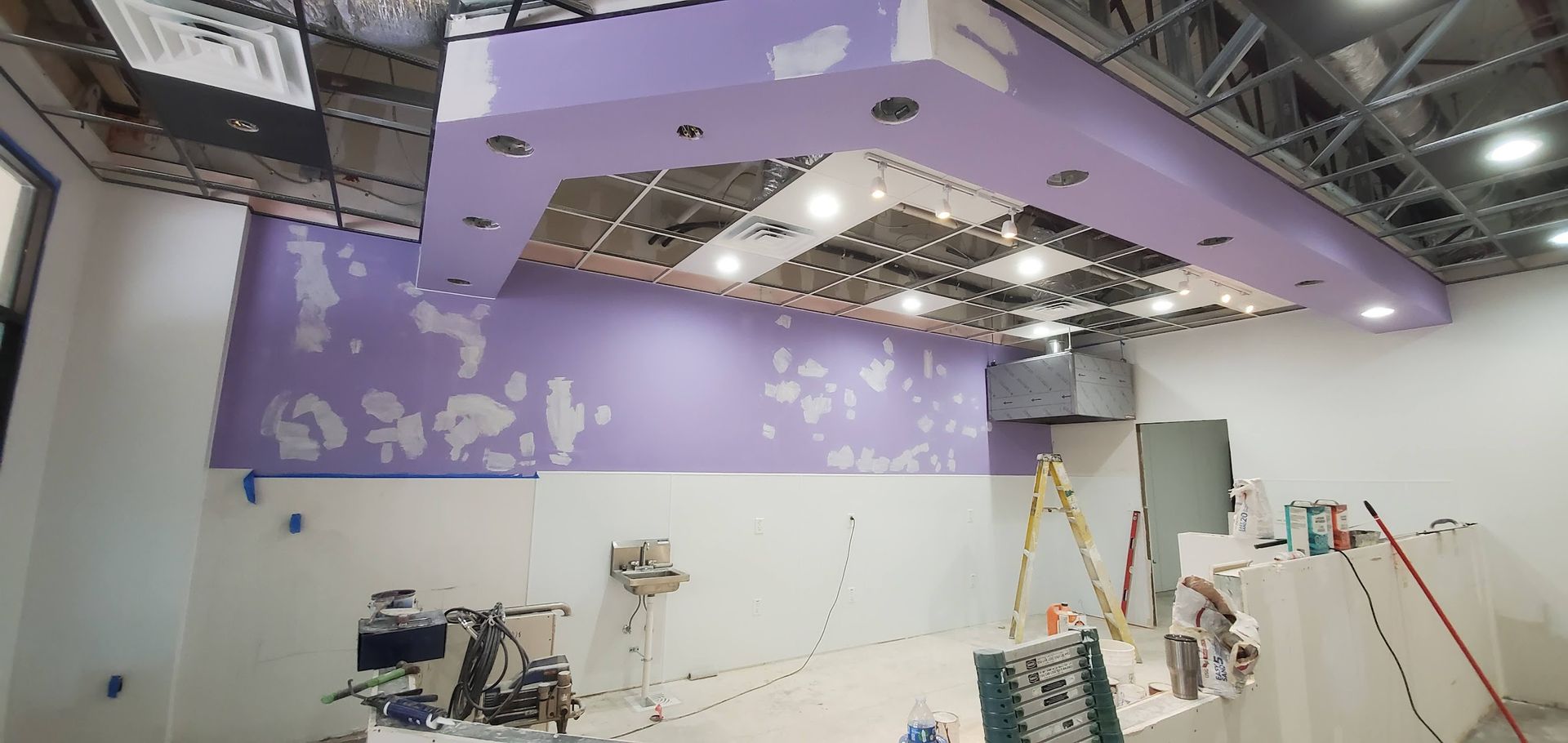 A room with a purple wall and a ceiling that is being painted.
