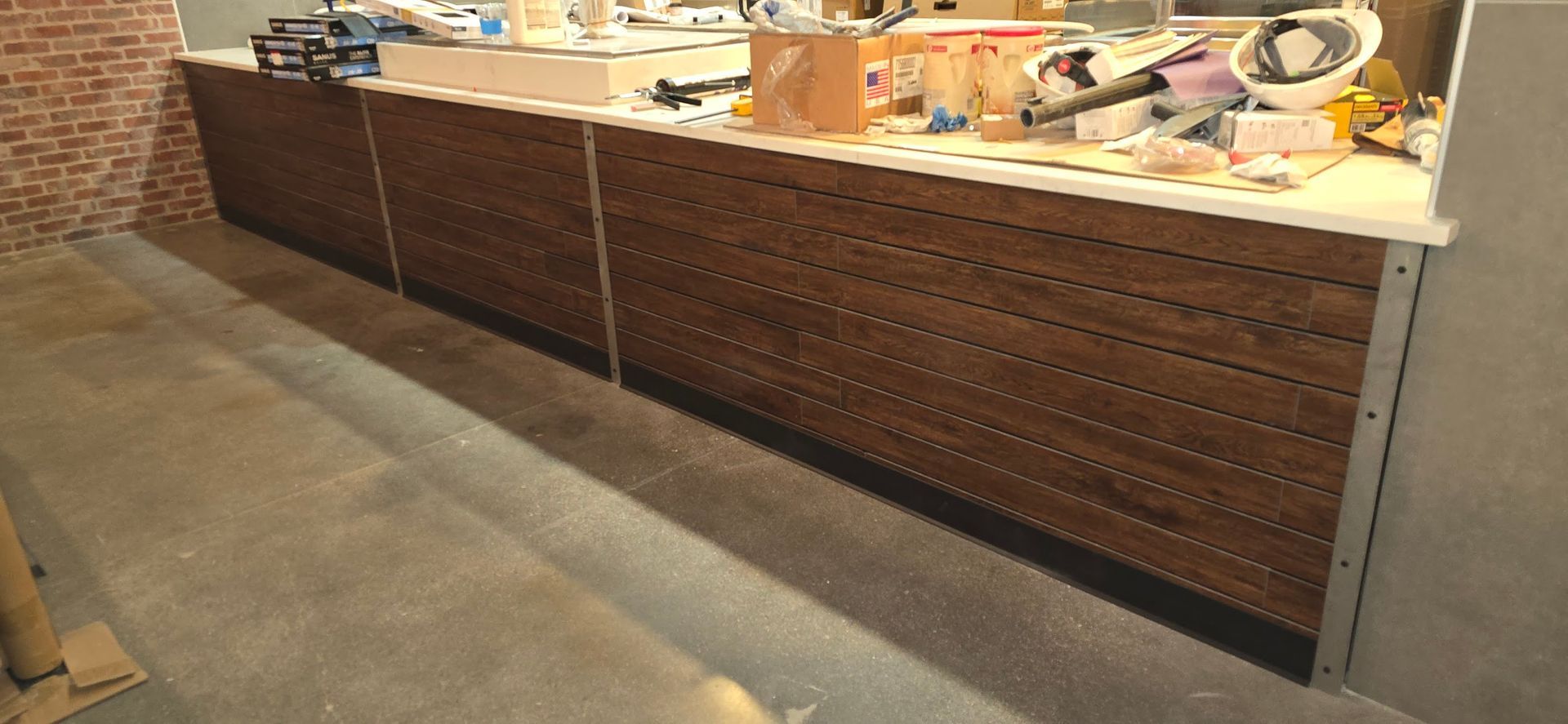 A long wooden counter in a room with a brick wall.