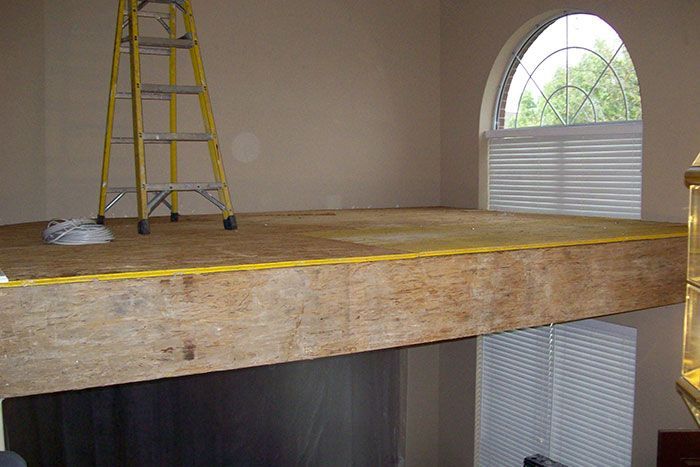 A ladder is sitting on top of a wooden platform in a room.
