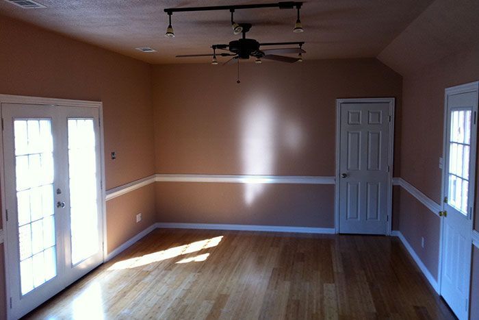 An empty room with hardwood floors and a ceiling fan