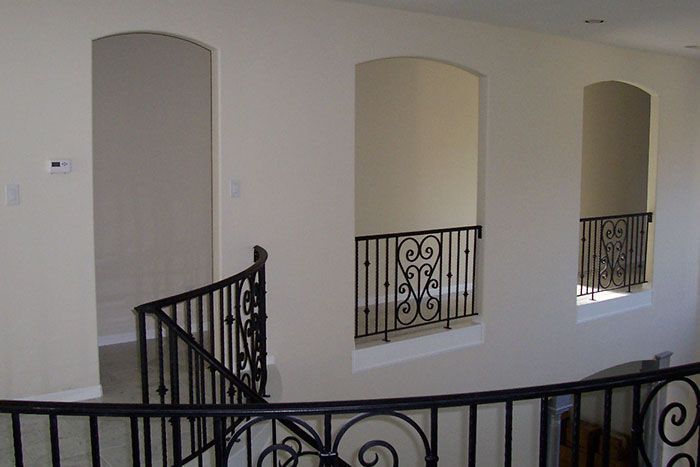 A staircase with a wrought iron railing and arched windows