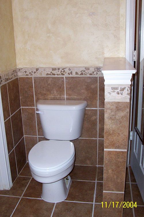 A toilet in a bathroom with tiles on the wall and floor