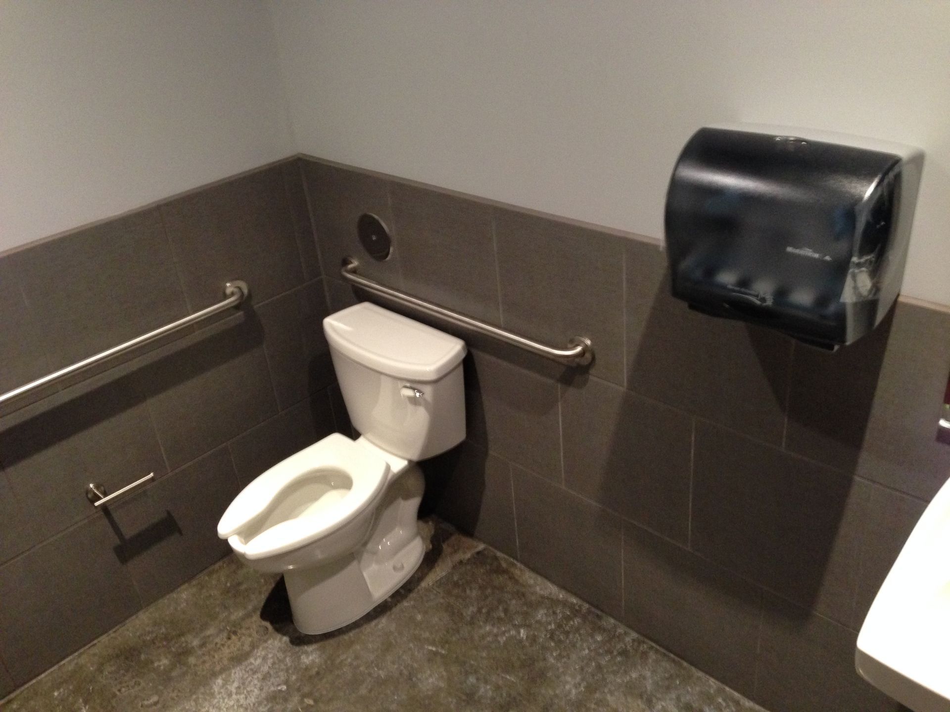A bathroom with a toilet and a paper towel dispenser