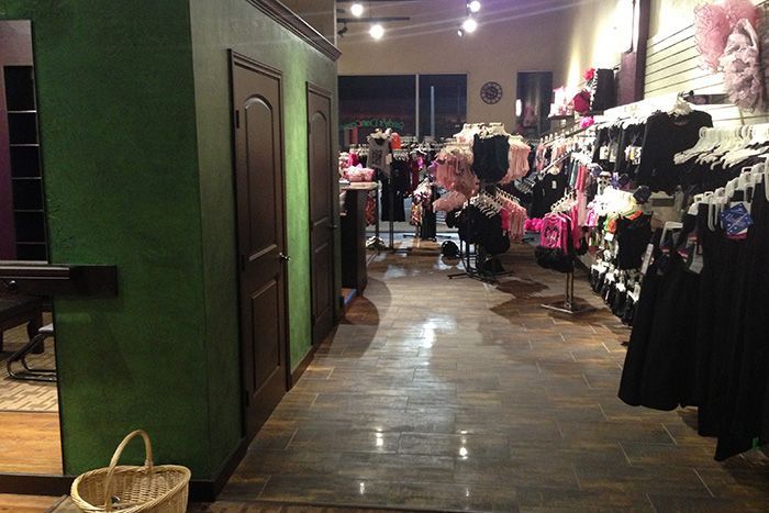 A store filled with lots of clothes and a basket on the floor.