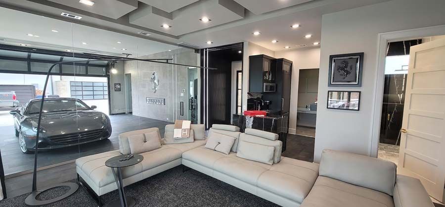 A living room with a couch and a car parked in the garage.