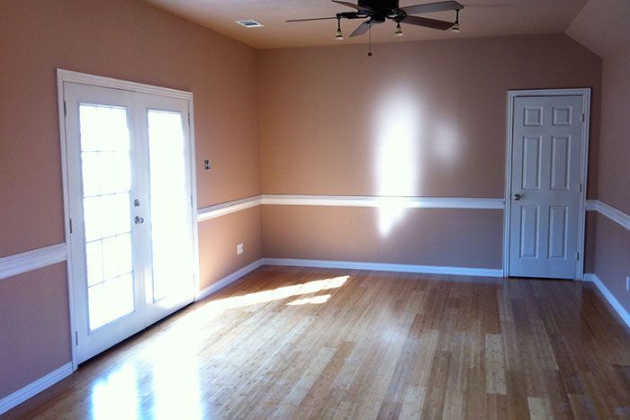 An empty living room with hardwood floors and a ceiling fan