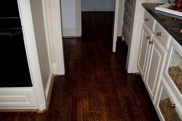 A kitchen with hardwood floors and white cabinets