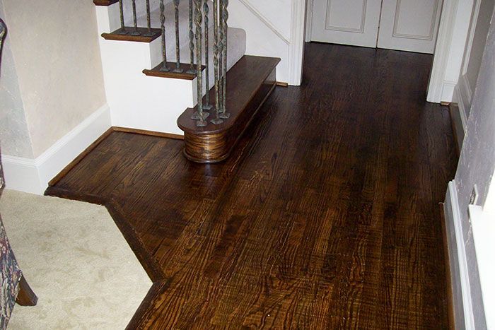 A hallway with stairs and a wooden floor