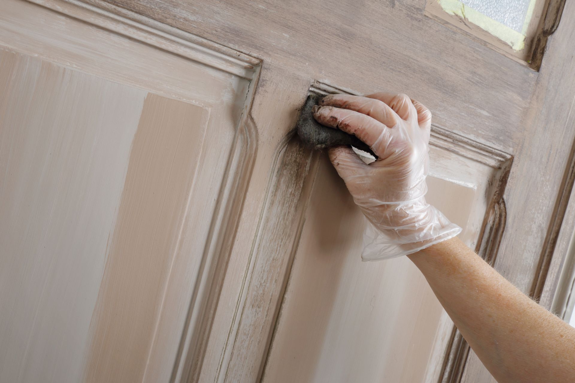 A person is sanding a door with a sponge.