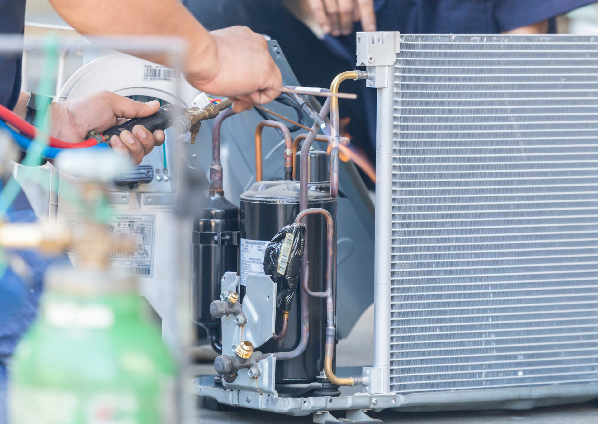 A man is working on an air conditioner with a wrench.