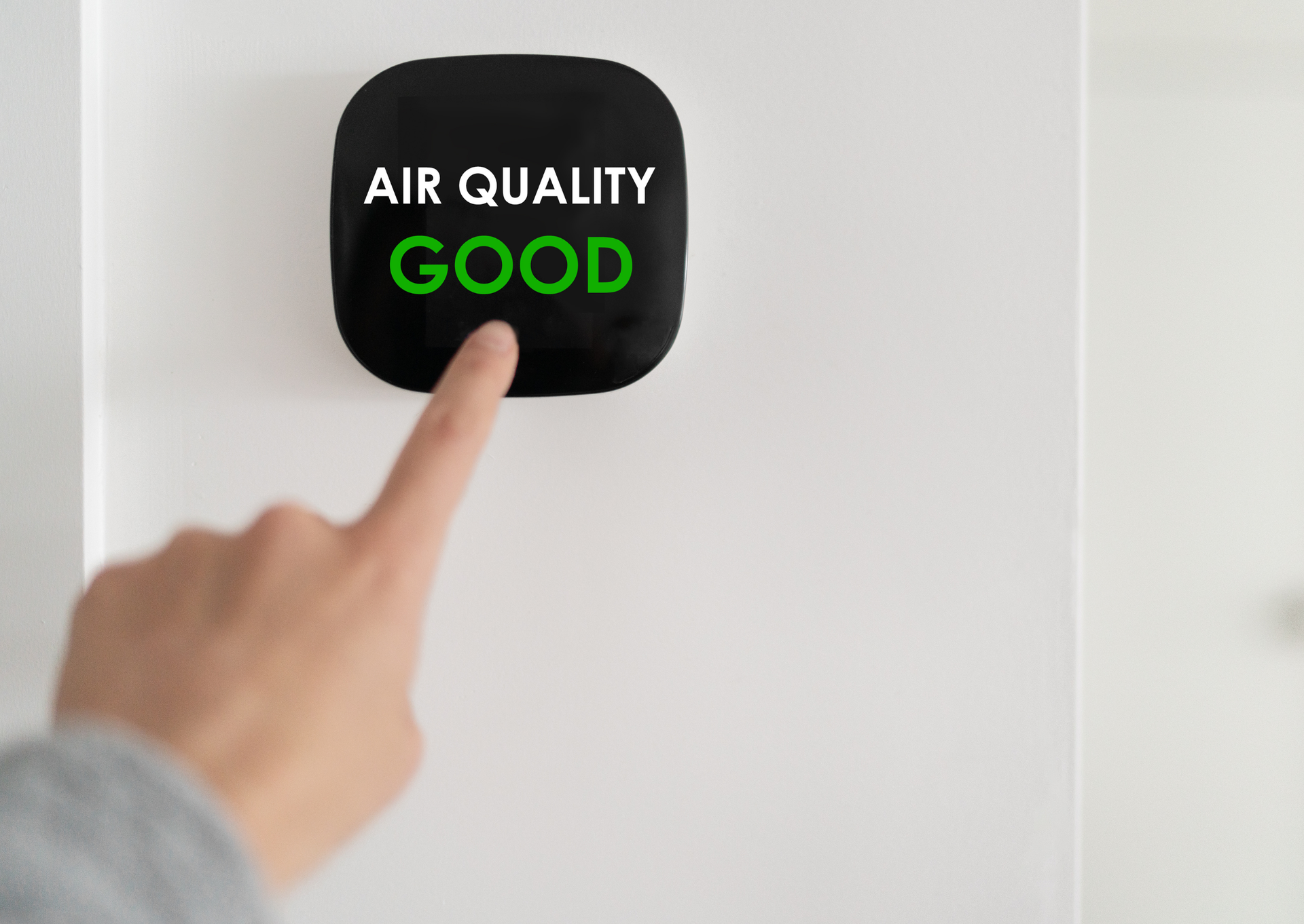 A person is pressing a button on a wall that says air quality good.