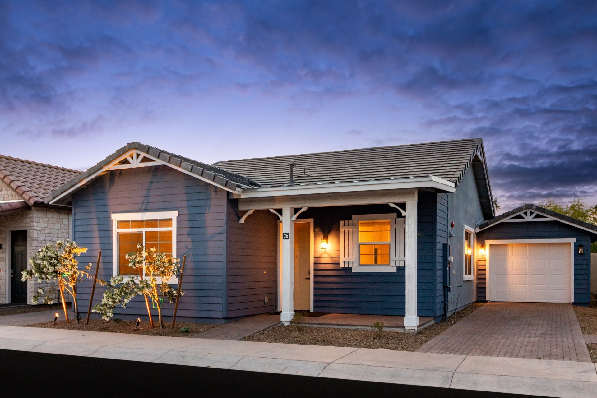 A blue house with a white porch and a garage