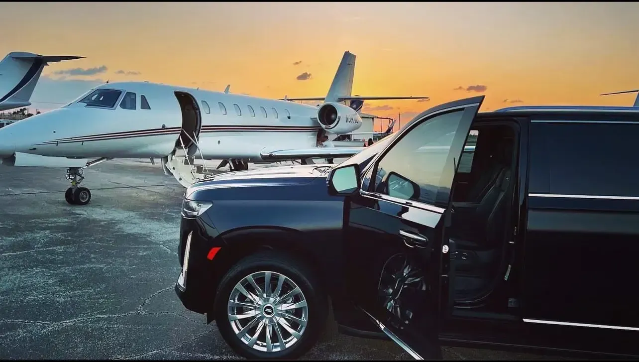A black suv is parked in front of a private jet
