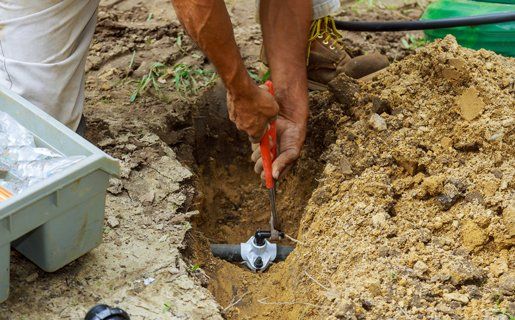 Sprinkler Repair — Man Working With Pipes Underground in Twin Falls, ID