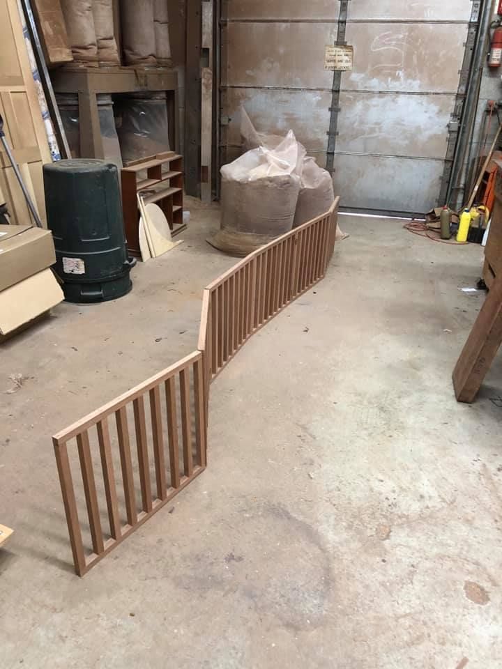 A wooden railing is sitting on the floor in a garage.