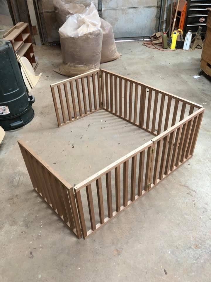 A wooden fence is sitting on the floor in a garage.