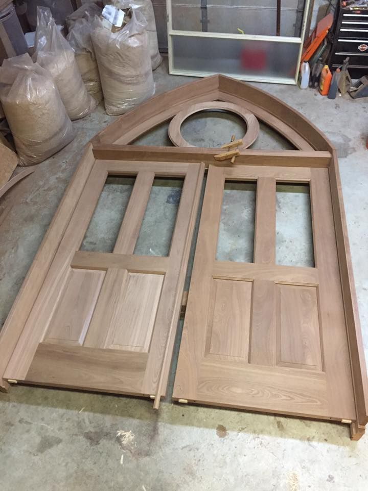 A wooden door is sitting in front of a white house.