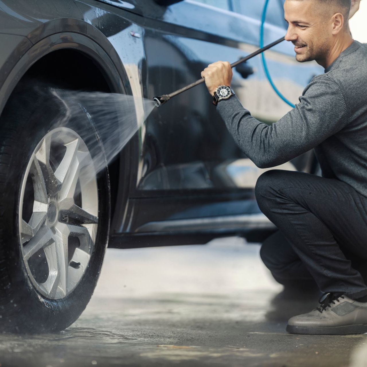 man spraying car tire in self serve car wash