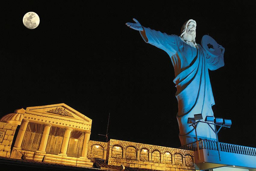 Cristo Luz iluminado à noite em BC com a lua ao fundo.