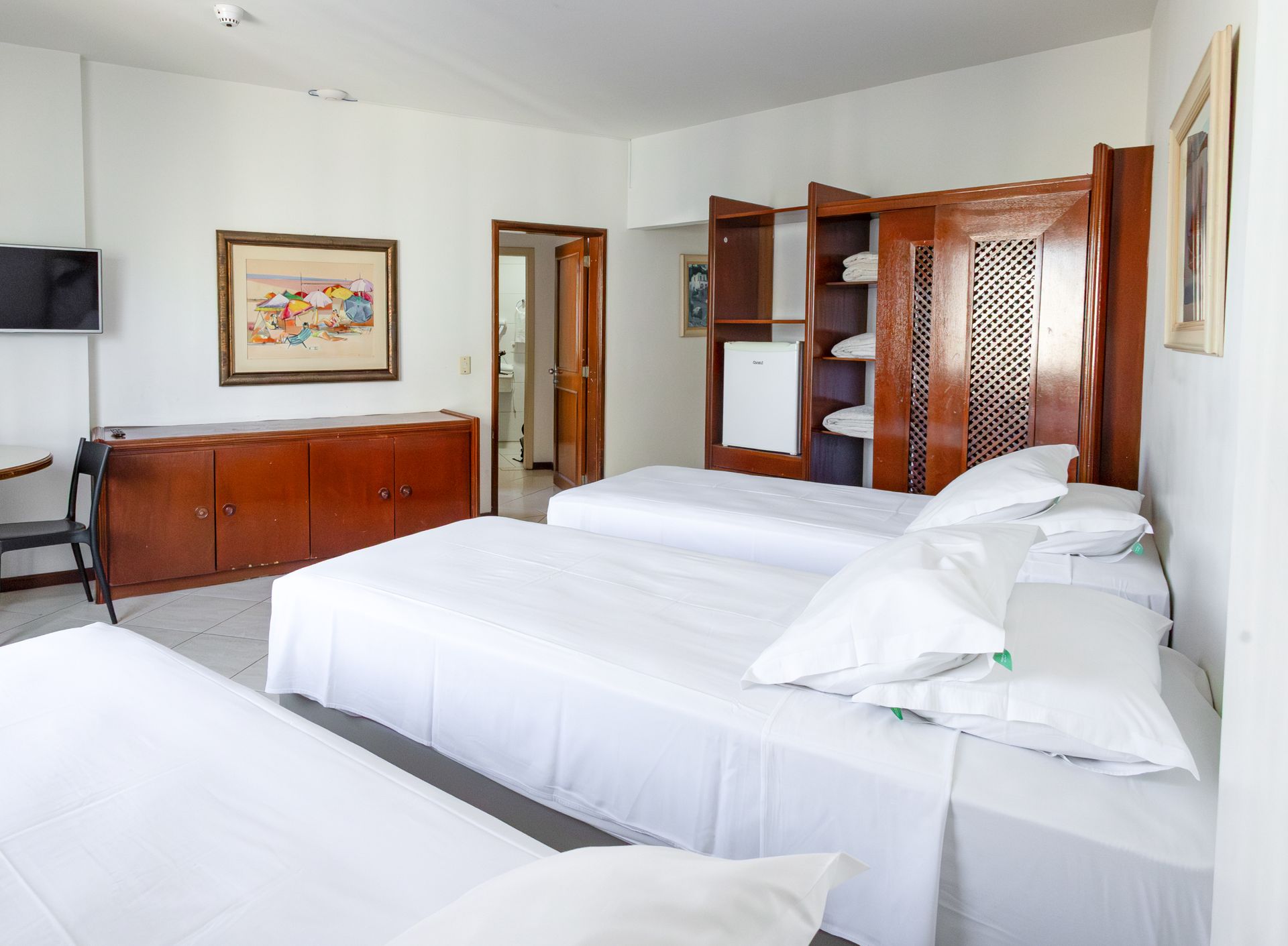 Quarto de hotel espaçoso com mesas, tv, armários e camas