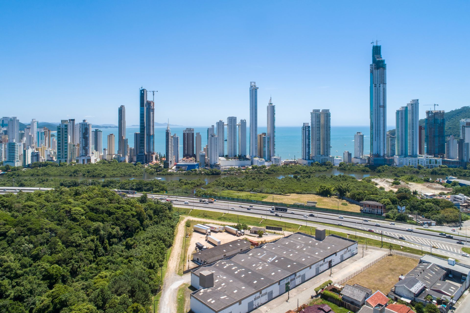 Vista aérea de Balneário Camboriú com prédios altos e área verde ao redor.