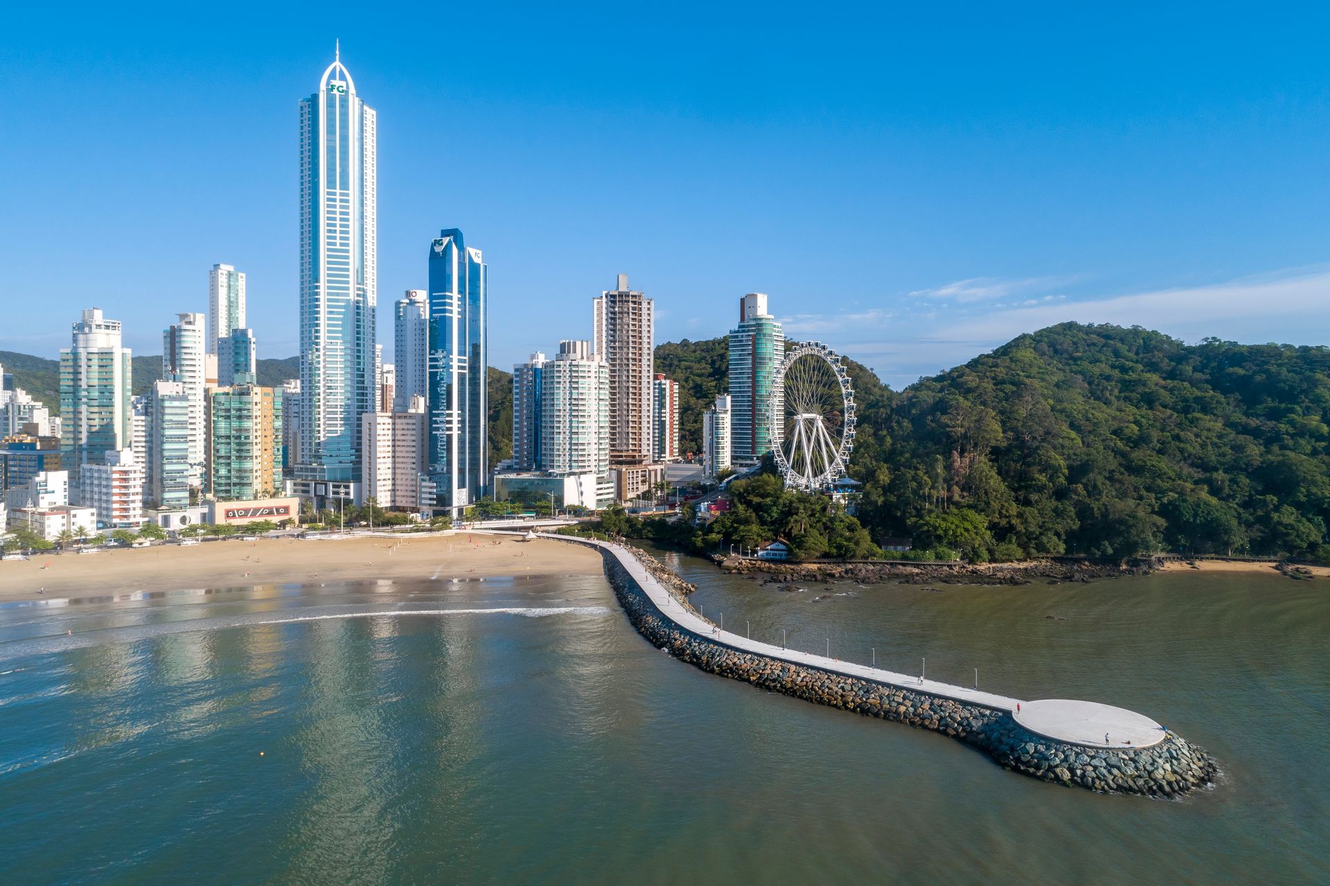 Vista aérea do molhe da Barra Norte e da roda-gigante sob o céu azul de Balneário Camboriú