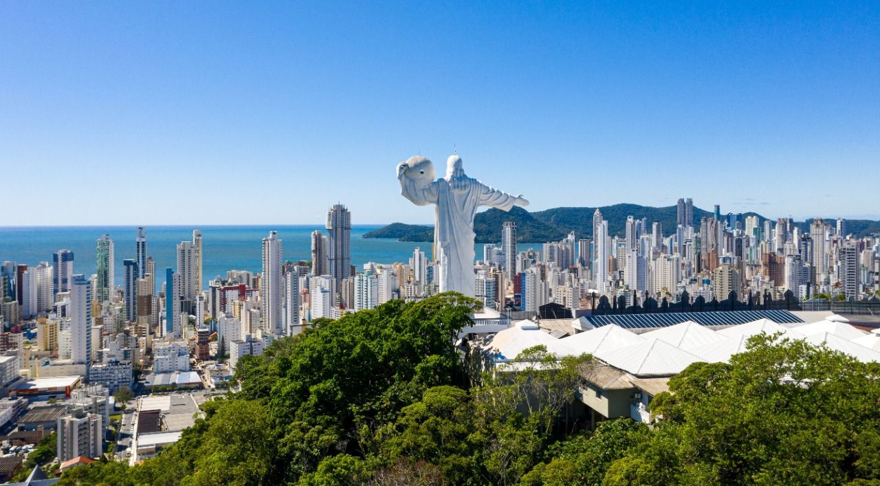 Estátua do Cristo Luz sobre prédios de BC com o mar ao fundo.